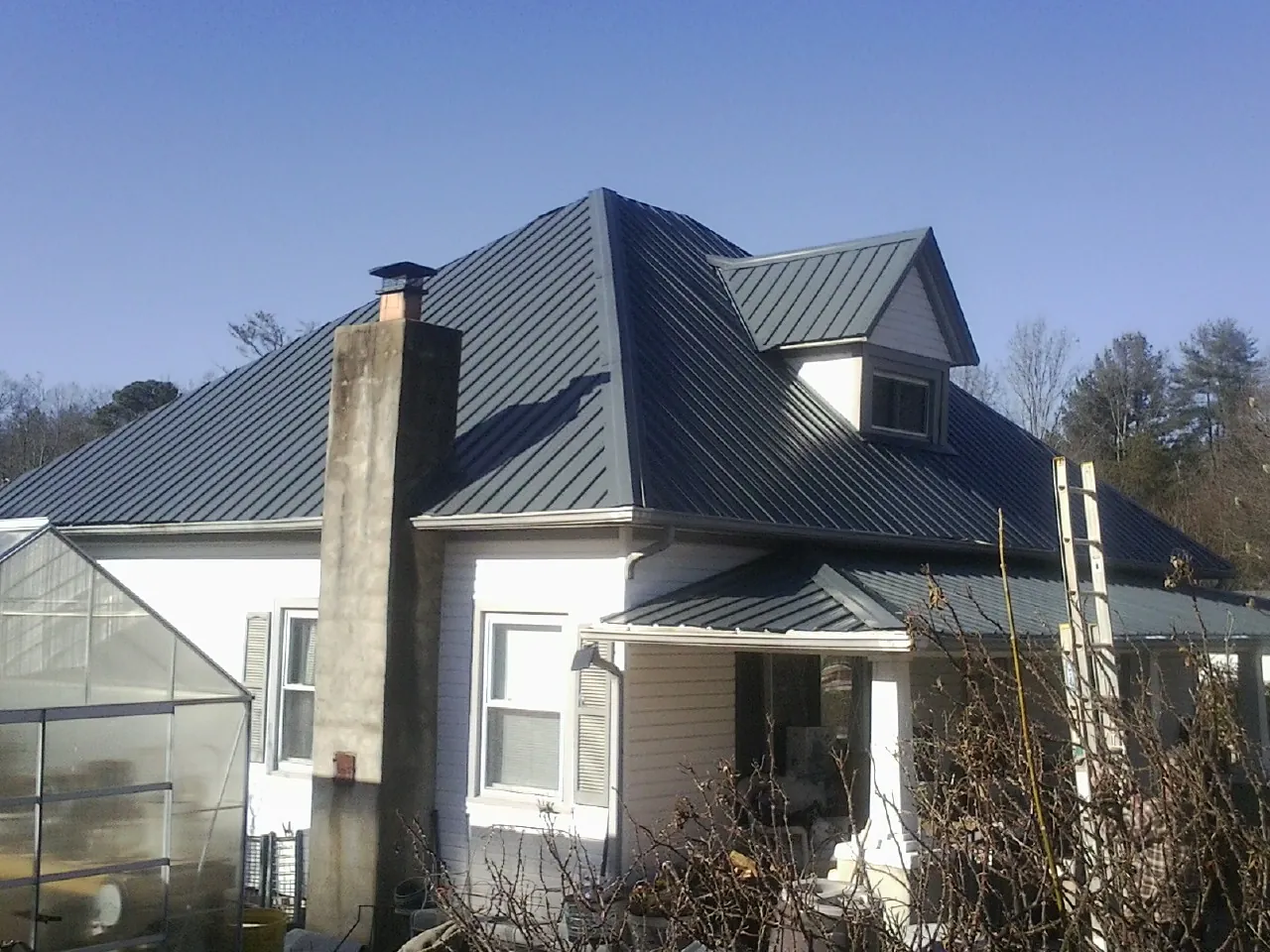 Dark blue standing seam metal roof on a white farmhouse with dormer — Slate & Tile Roof Repair by Roofing Brothers in Verplanck