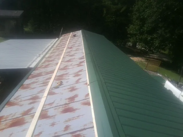 Old rusted panels beside newly installed green metal roofing — Wind Damage Roof Repair by Roofing Brothers in Verplanck