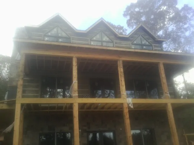 Dormers and porch framing on a large log home under construction — Roof Coating work by our crew in Verplanck