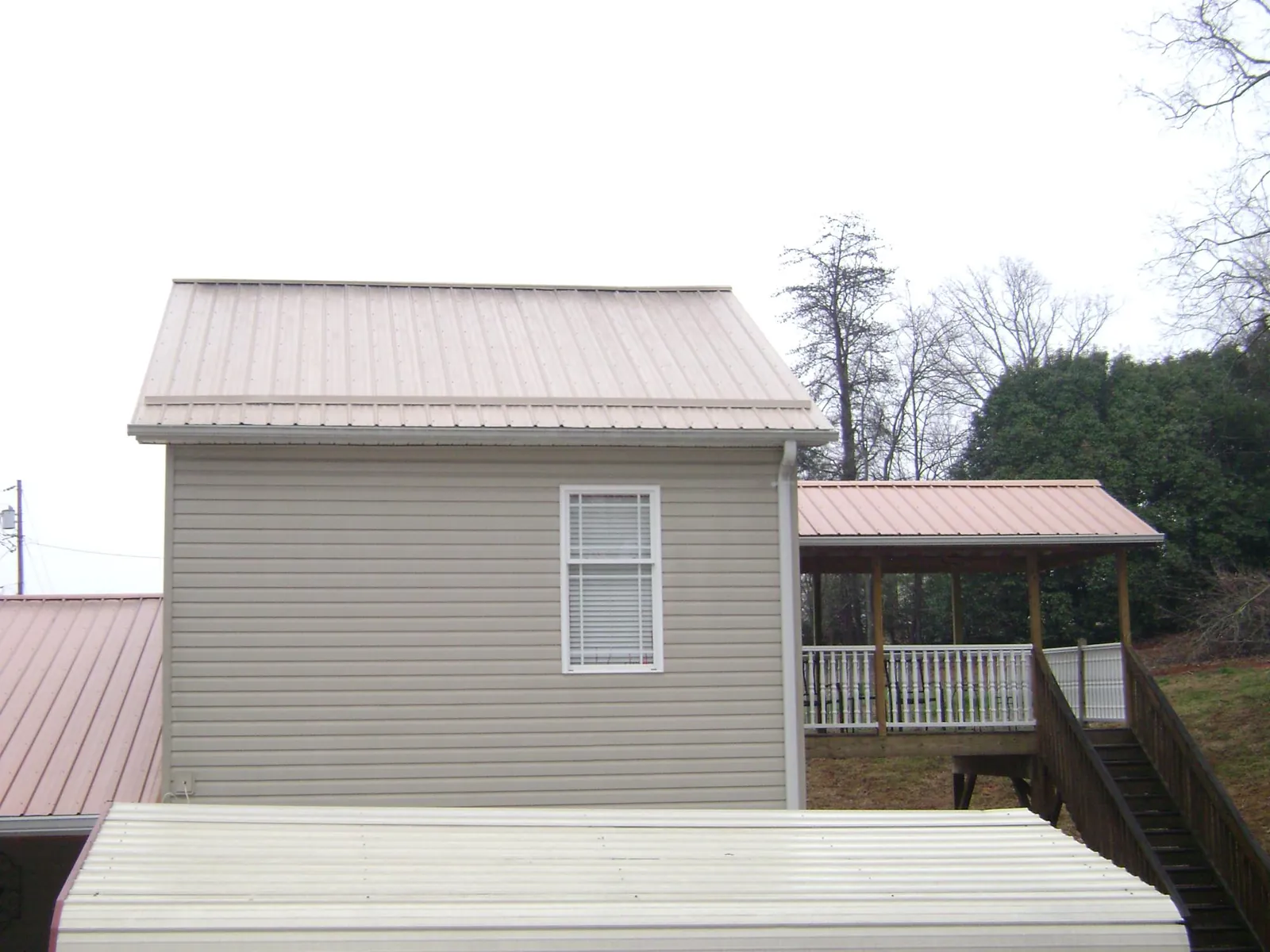 Tan metal roofs on a two story addition and attached porch, from a Roof Replacement job in Verplanck