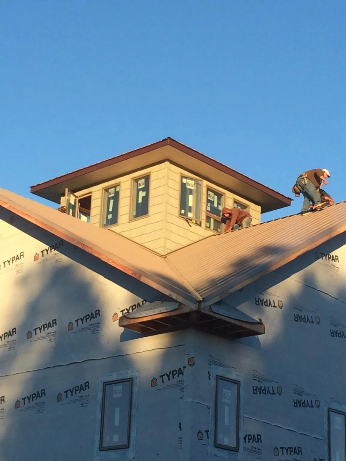 Roofers working around a rooftop cupola on a new metal roof at sunset — Roof Waterproofing in Verplanck by Roofing Brothers